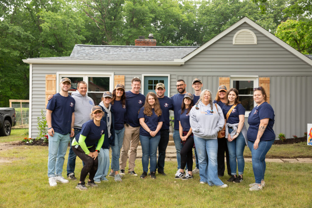 The Third Estimate team standing with Dillon and Keslie in front of the home makeover house.