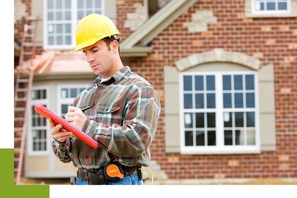 A contractor writing on a notepad in front of a home with freshly installed windows.